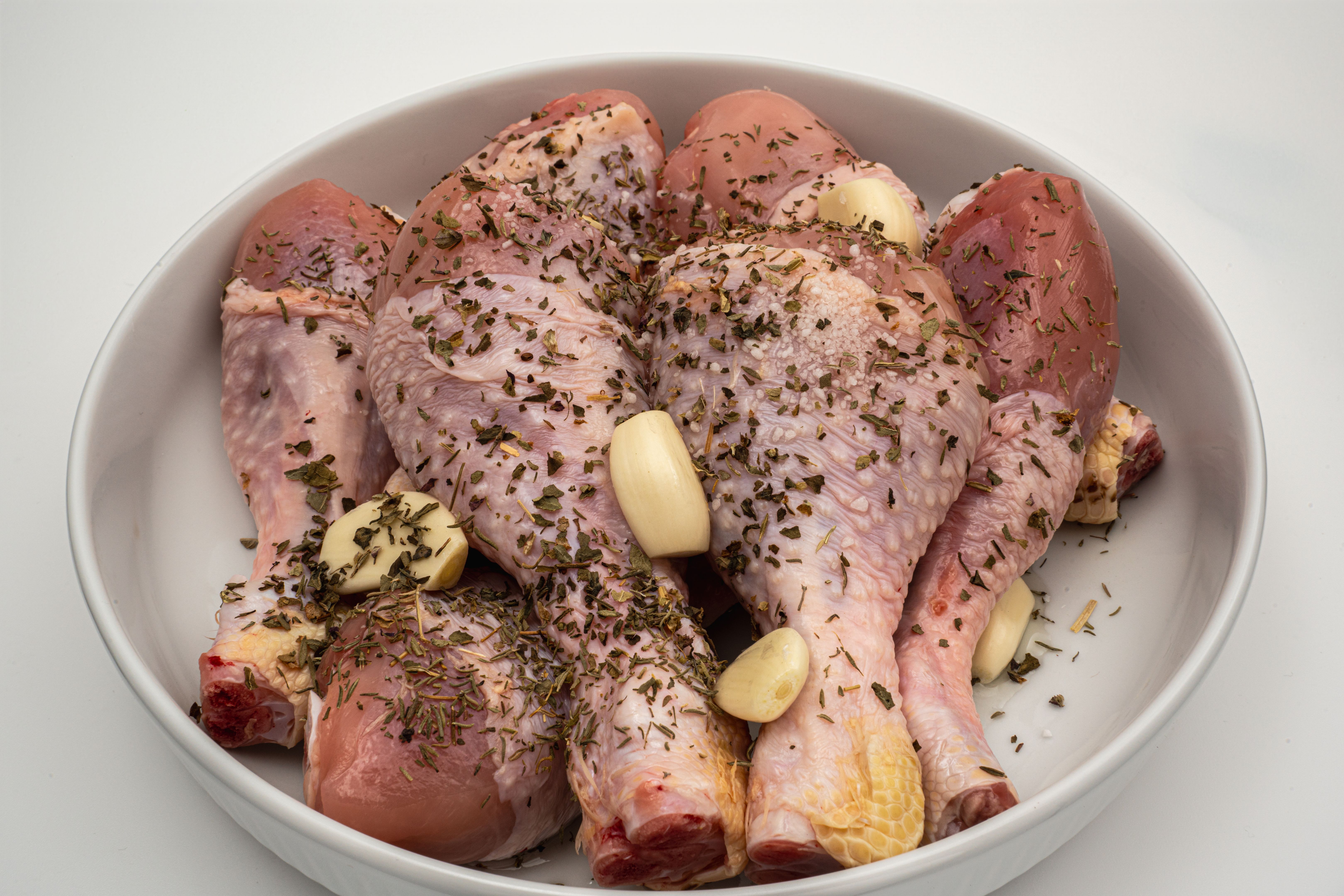 Chicken drumsticks seasoned with herbs and garlic before cooking for dinner preparation Chicken drumsticks seasoned with herbs and garlic before cooking for dinner preparation