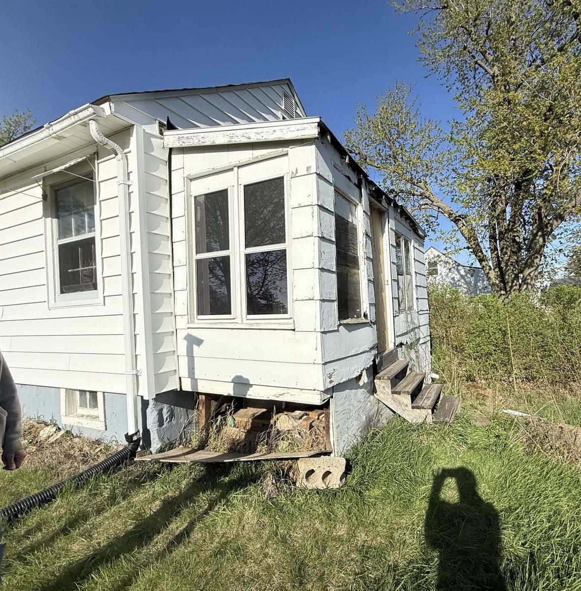 Before: a rotting add-on with damaged siding and boarded windows, before Urban Edge Construction rebuilt it as a new home addition