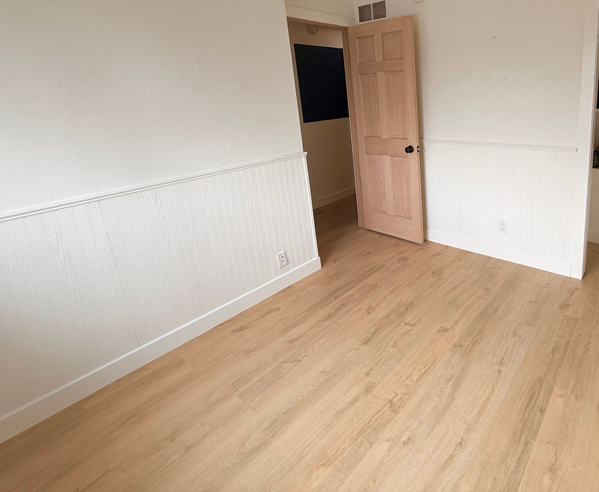 Light oak LVP flooring installed in a Cedar Rapids living room with white wainscoting