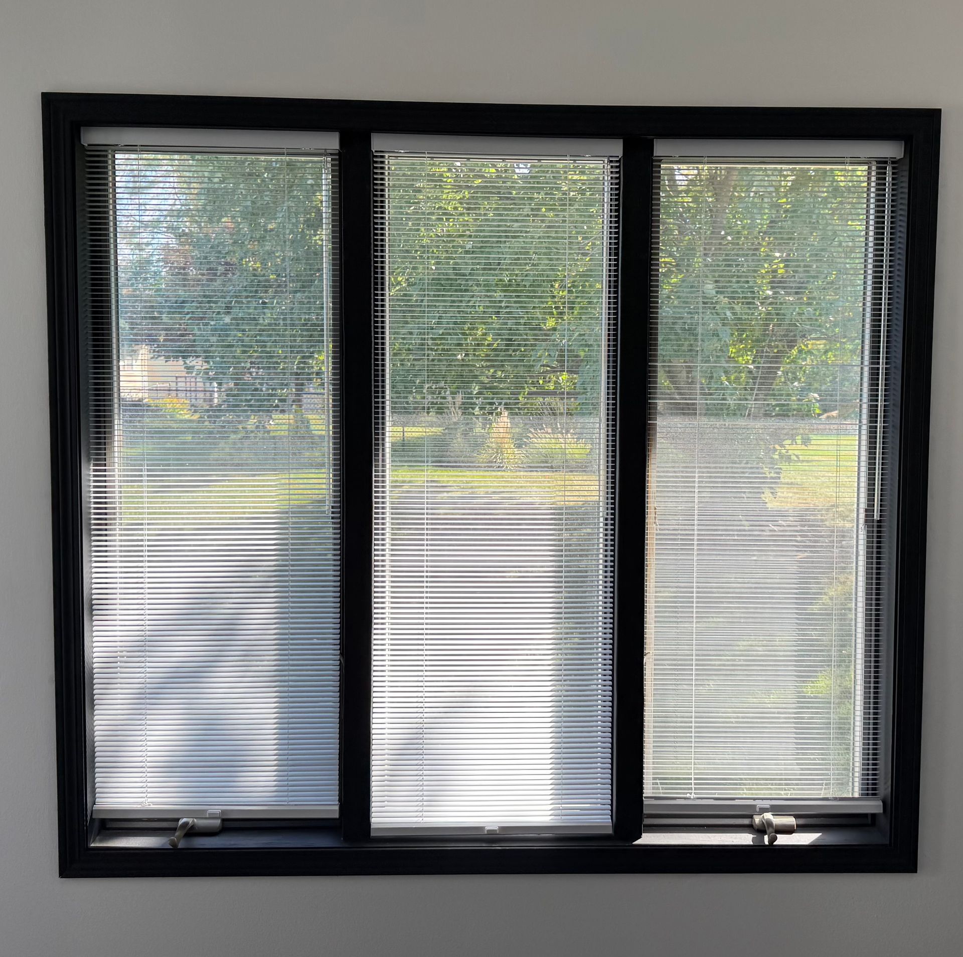 New window with black interior trim and blinds installed by Urban Edge Construction in Cedar Rapids, Iowa