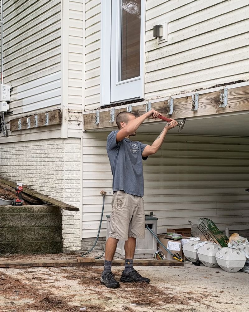 Matt of Urban Edge Construction & Remodeling repairing a deck ledger with new joist hangers in Cedar Rapids, Iowa
