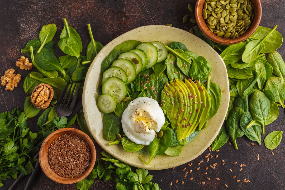 Green salad with spinach, avocado, egg, flax and pumpkin seed. Food background. Detox Vegetarian Healthy Food Concept. Top view, copy space.