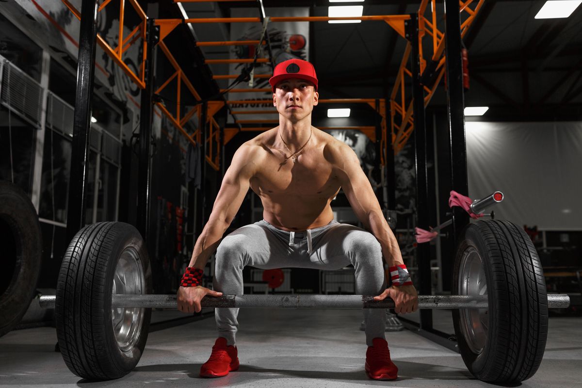 Muscular fitness man preparing to deadlift a barbell over his head in modern fitness center.Functional training.Snatch exercise
