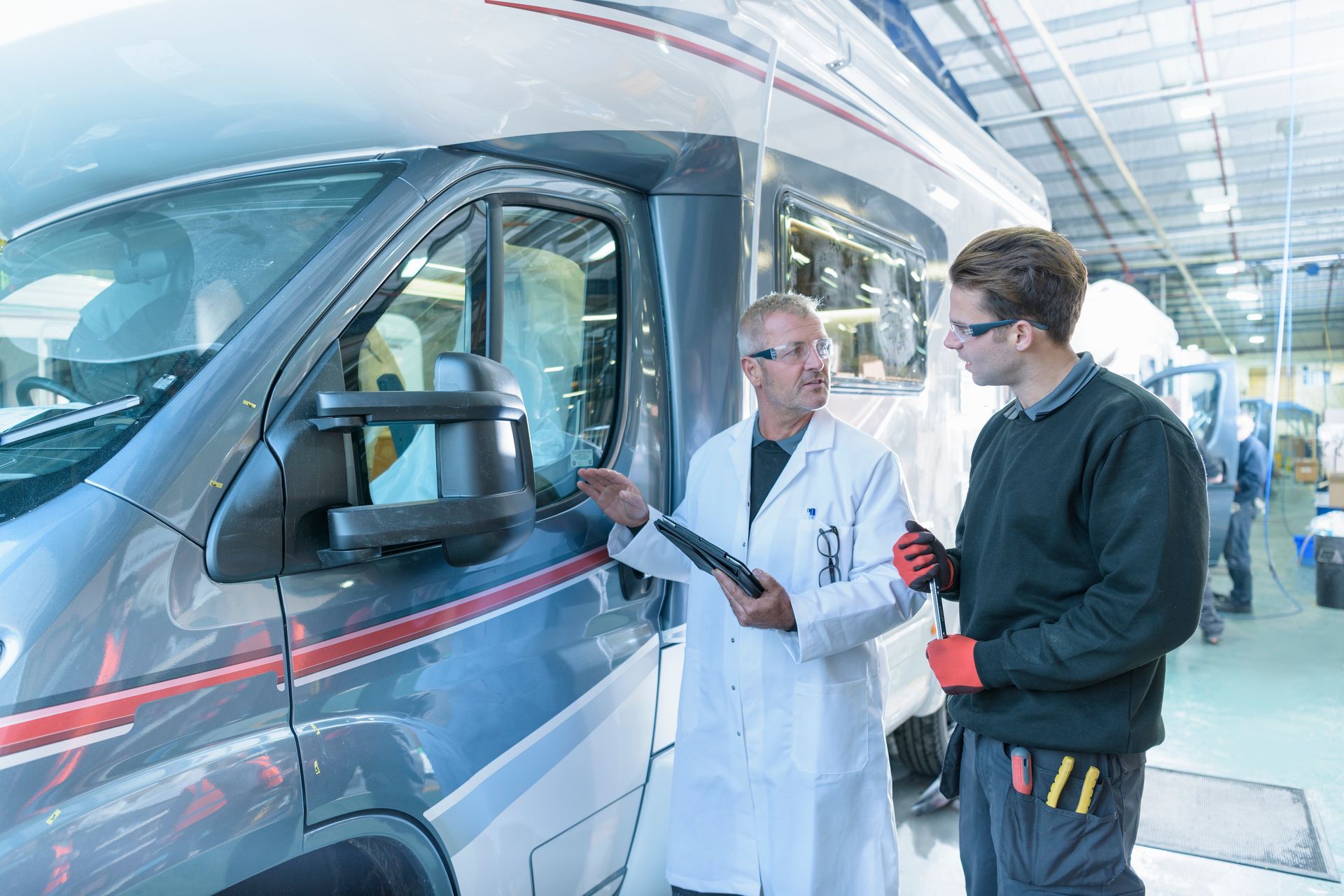 Workers inspecting vehicles on motorhome production line