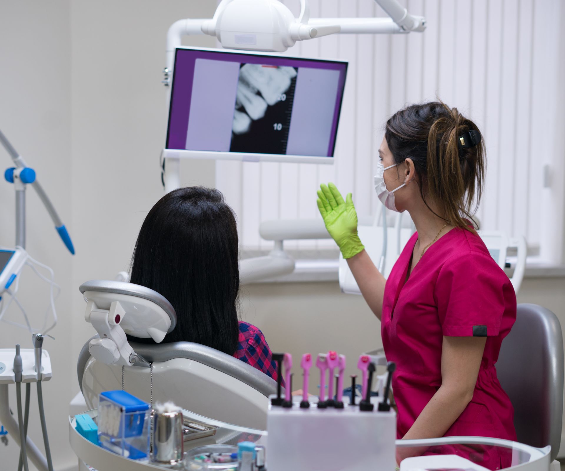 Dentist at work showing woman's teeth on big screen in dental clinic. New dental technologies.