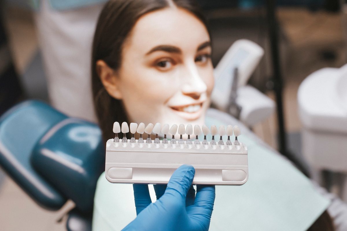 Closeup of a girl with beautiful smile at the dentist. Dental. Dentist matching teeth colour in office. Beautiful Model Girl with white teeth and perfect skin. Teeth whitening.
