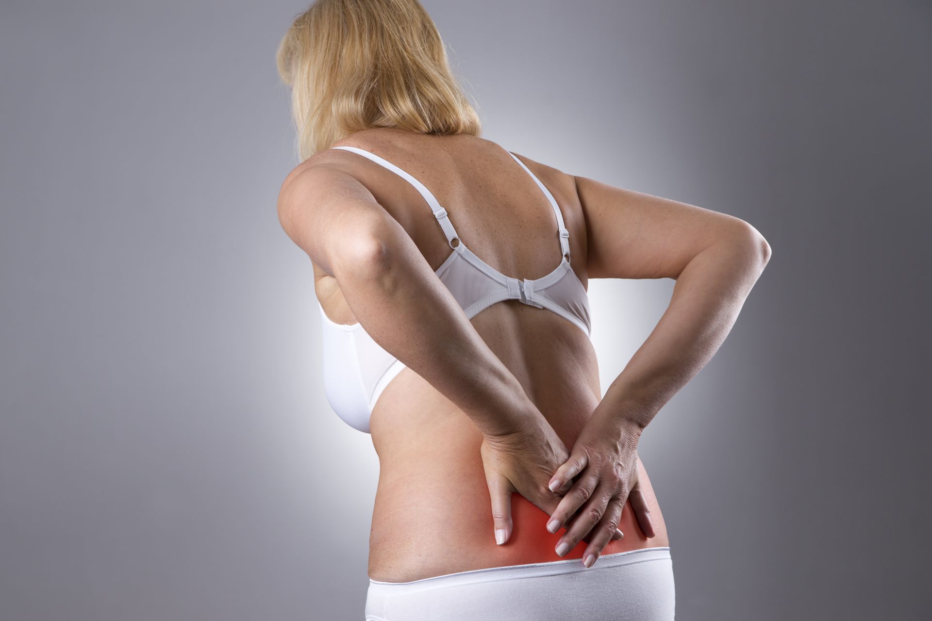 Woman with backache. Pain in the human body on a gray background with red dot