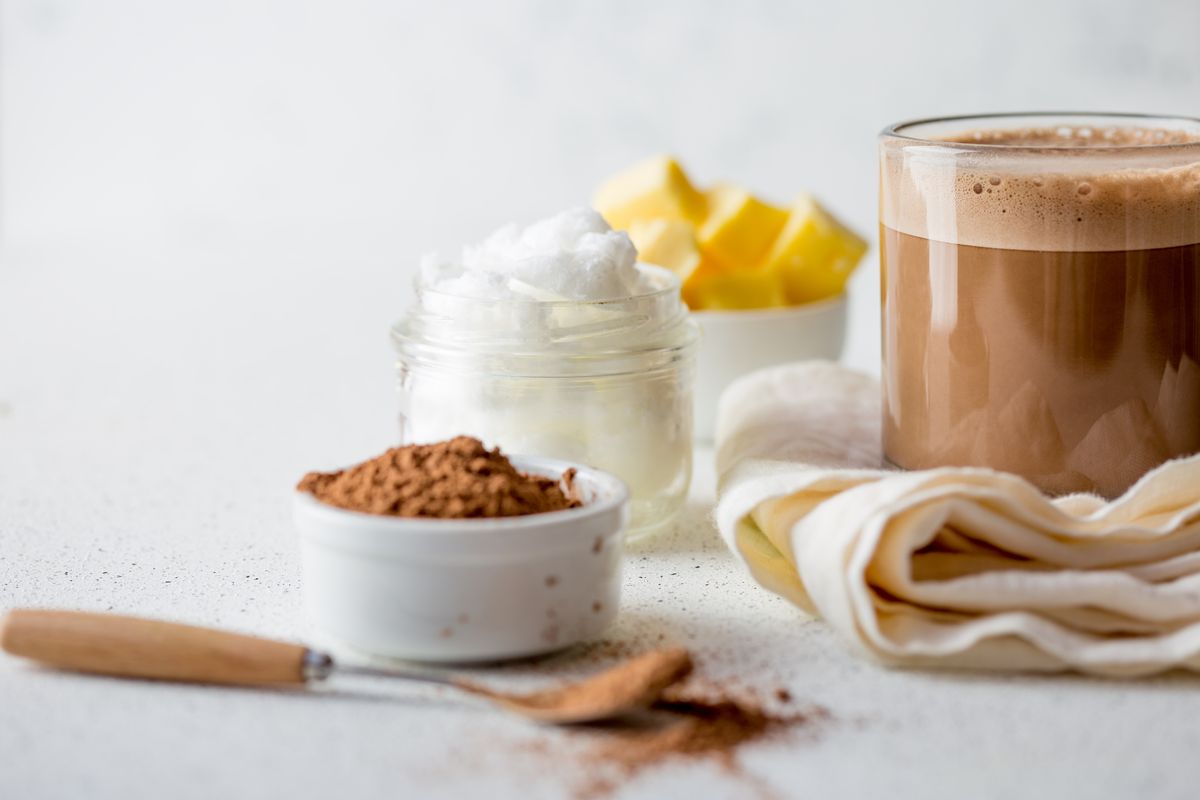 BULLETPROOF CACAO. Ketogenic keto diet hot drink. Cacao blended with coconut oil and butter. Cup of bulletproof cacao and ingredients on white background.