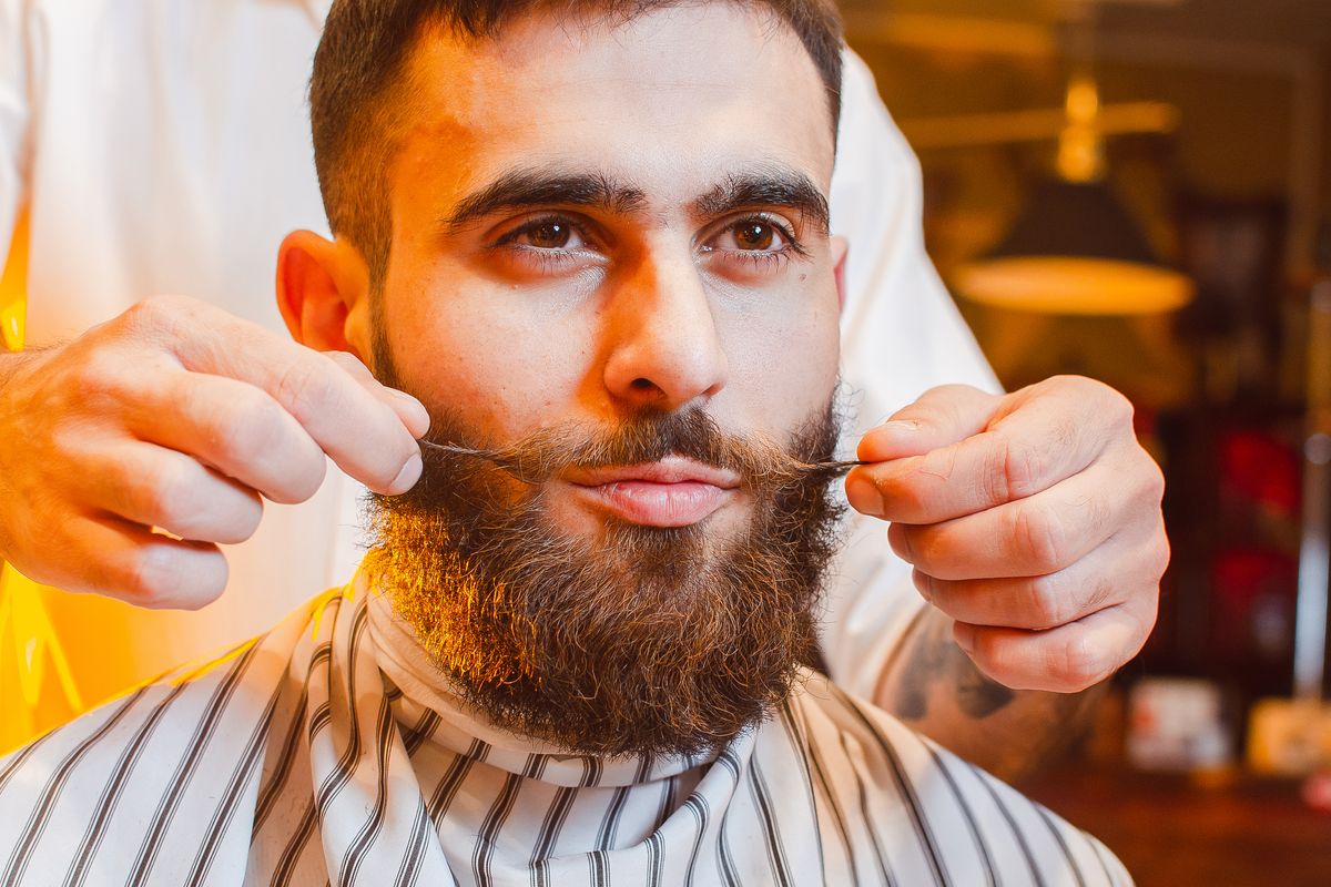 Barber makes a styling mustache for a young handsome guy in a male barber shop. Barber Shop. Barber makes a styling mustache for a young handsome guy in a male barber shop. Barber Shop.