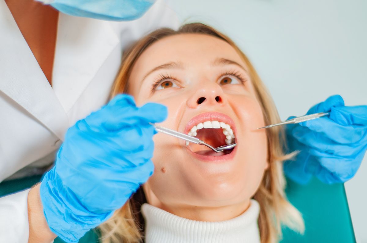 Woman having teeth examined at dentists . Doctor doing dental treatment