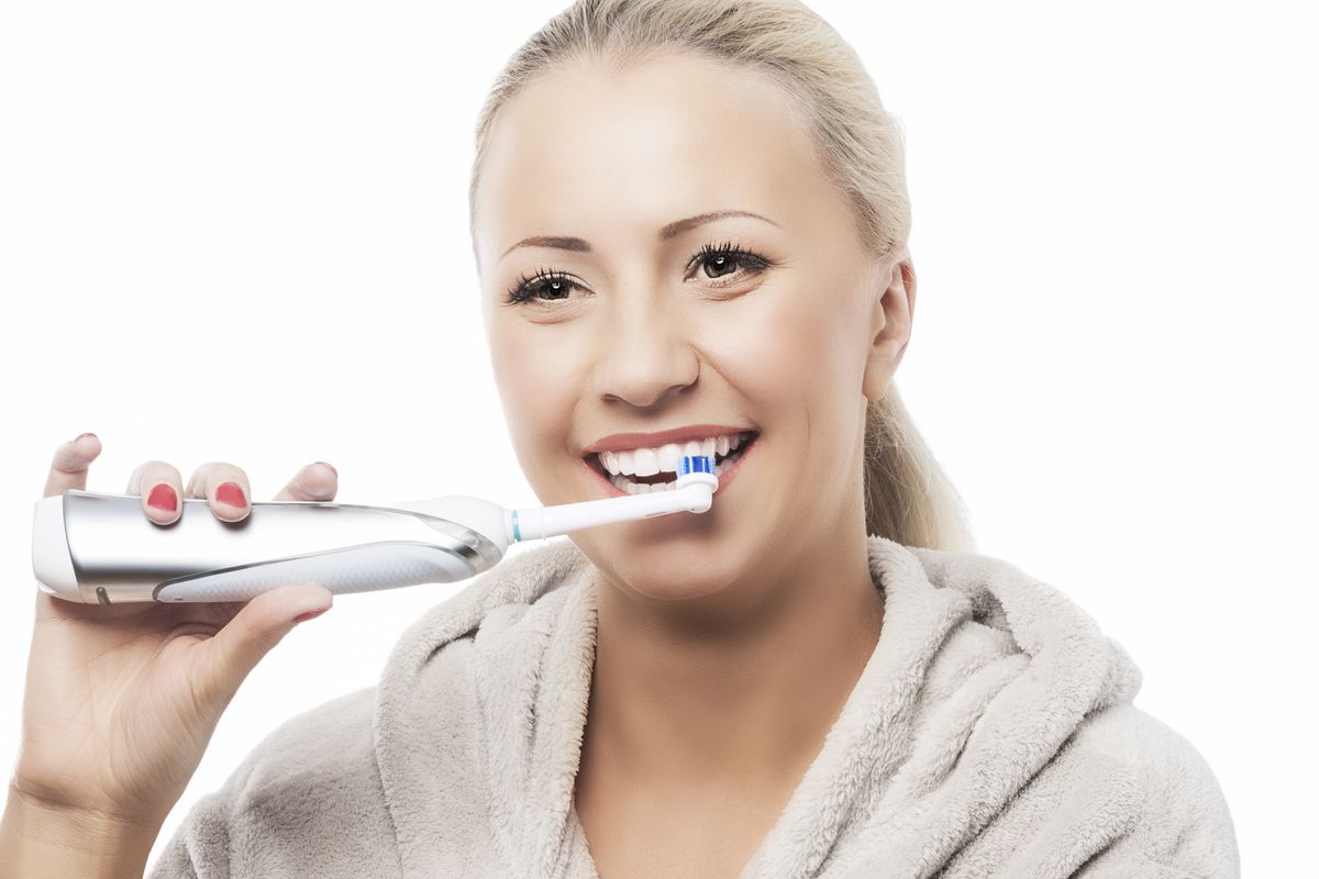 Dental Hygiene Concept:Caucasian Woman Brushing Her Teeth With Modern Electric Toothbrush. Against Pure White Background. Horizontal Image
