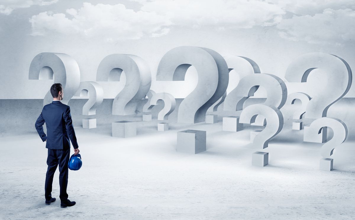Businessman standing and looking to a bunch of question mark signs